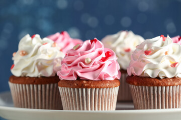 Stand with tasty cupcakes for Valentine's Day on blurred blue background