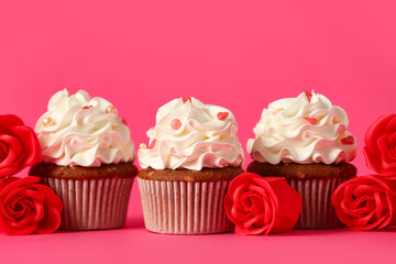 Tasty cupcakes with rose flowers for Valentine's Day on pink background