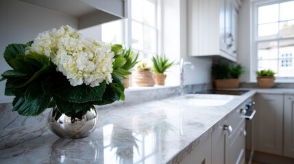 White hydrangeas in a silver vase on a marble countertop in a bright kitchen