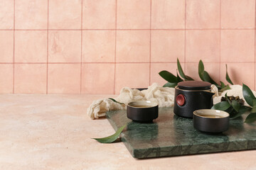 Cups of hot tea and teapot on light background
