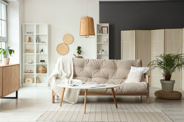 Interior of modern living room with soft sofa, shelving unit and coffee table