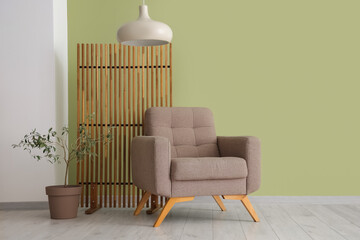 Beautiful interior of living room with soft armchair, houseplant and folding screen
