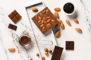 Sweet chocolate with almond nuts, hazelnuts and cocoa powder on white background