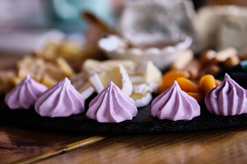 Delicious assortment of meringues and snacks presented on a rustic wooden table at a cozy gathering