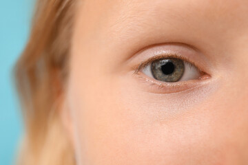 Teenage girl on blue background, closeup. Children's Eye Health and Safety Awareness Month