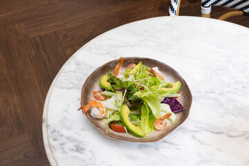 Fresh salad with feta cheese avocado,shrimp and olives on a plate