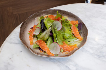 Fresh salad with shrimps and salmon served with vegetables on a plate