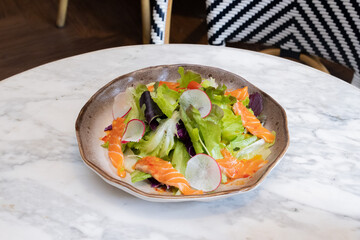 Fresh salad with shrimps and salmon served with vegetables on a plate