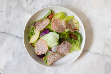 Tuna salad sandwich and ham and cheese sandwich served on a plate with fresh vegetables