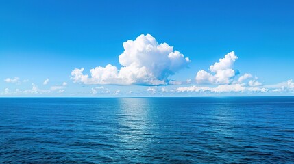 A single cloud shadow stretches over the calm ocean under bright sunlight; the sun shines warmly, the sky is clear and blue, the water's surface is smooth and still, and the interplay of light and sha