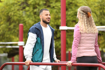 Sporty young woman with trainer doing physical exercise in park