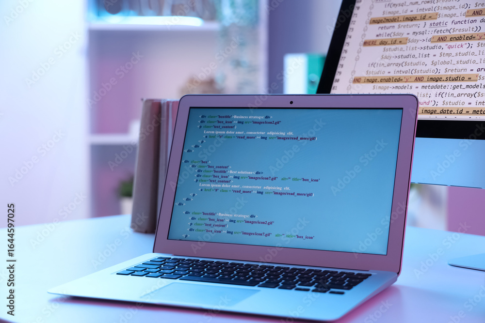 Poster laptop with code on programmer's desk in office, closeup