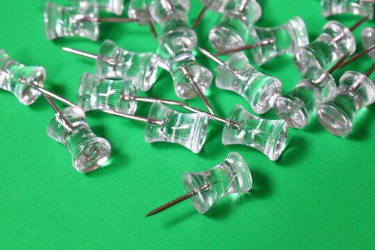 clear push pins on green background - Powered by Adobe