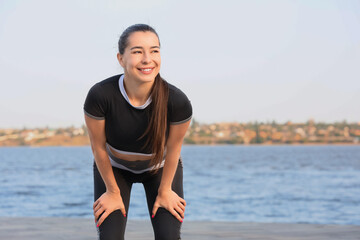 Sporty young woman running on embankment