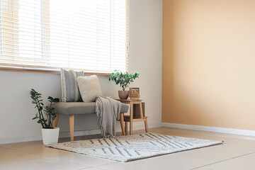 Soft bench with pillows, plaid and plants near window in room