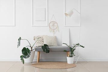 Interior of light room with soft bench, plants and lamp