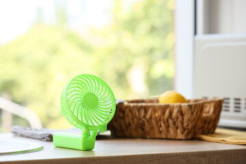 Green mini fan on table in kitchen, closeup