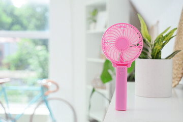 Pink mini fan on shelf in room, closeup