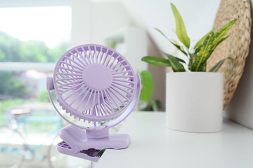 Lilac mini fan on shelf in room, closeup