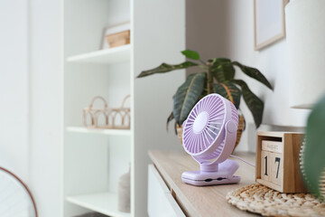 Lilac mini fan on shelf in room, closeup