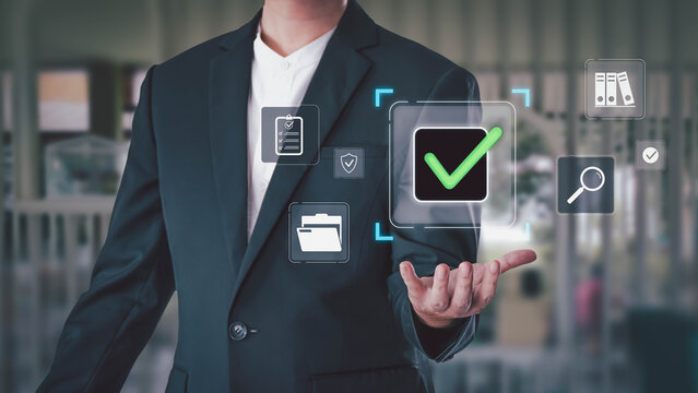 Businessman hand showing virtual screen with green check mark for approval. Concept of quality control, ISO certification, document management, and business process automation in a modern office.