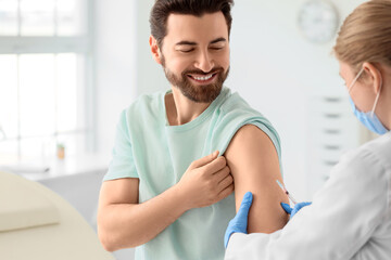 Young man receiving vaccine from doctor in clinic