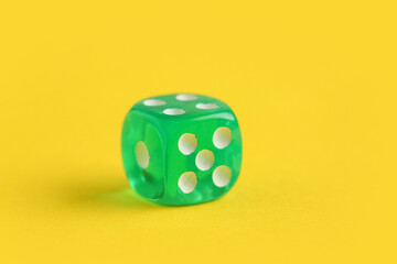 Green game dice on yellow background