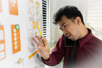 A man is working on a mobile user interface design project. He is focused on the task at hand and...