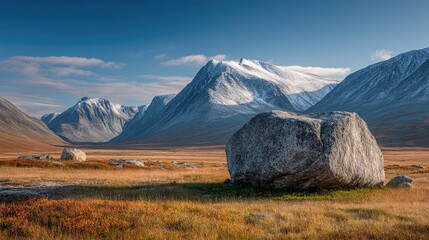 Majestic mountain range, a large boulder, and colorful autumnal meadow