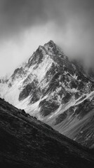 Obraz premium Gray mountain peak, snow-capped, dramatic clouds