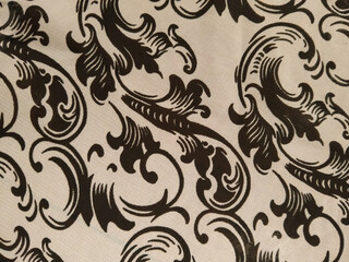 Black ornate floral patterns on a white fabric background, creating an elegant and classic...