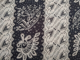 Traditional batik fabric with intricate floral and geometric patterns in black and white, showcasing classic Indonesian textile art.