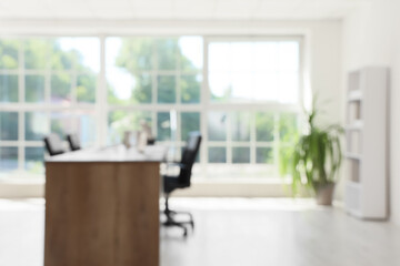 Blurred view of conference hall with desk, shelf unit and palm plant
