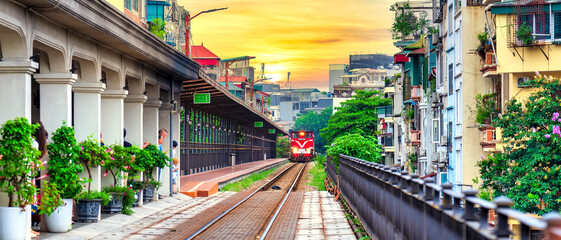 Train running on ancient railway at Long Bien bridge station in Hanoi, Vietnam with market community