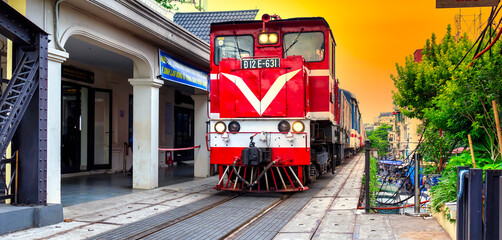 Train running on ancient railway at Long Bien bridge station in Hanoi, Vietnam with market community