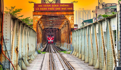 Train running on ancient railway at Long Bien bridge station in Hanoi, Vietnam with market community