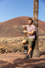 Musician Leaning Against Palm Tree Holding Trumpet in Volcanic Landscape