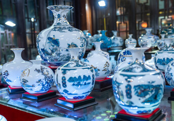 Traditional Vietnamese blue porcelain utensils with vases, dishes, altar items on dispenser at street market in Hoa Lu old city, Ninh Binh, Vietnam. Handmade souvenirs of crockery for daily use