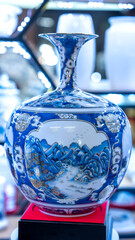 Traditional Vietnamese blue porcelain utensils with vases, dishes, altar items on dispenser at street market in Hoa Lu old city, Ninh Binh, Vietnam. Handmade souvenirs of crockery for daily use