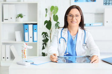 Female doctor with x-ray image of lungs at table in clinic