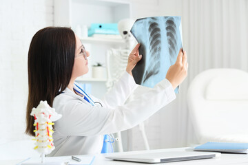Female doctor studying x-ray image of lungs at table in clinic