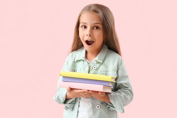 Surprised little girl with books on pink background