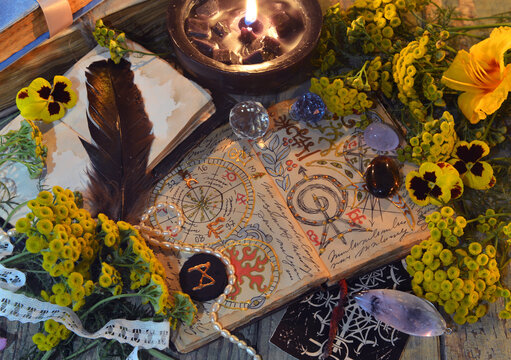 Mystic still life with decorated magic book of spells, tarot card, tansy flowers, crystals, black candles and witchy ritual objects. No foreign language, only fantasy symbols