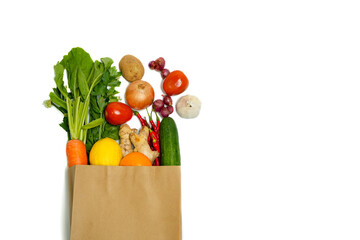 Reusable paper bag with fresh vegetables and spices: carrot, greens, celery, tomato, potato,...