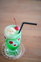 チェリーとバニラアイスをのせた鮮やかな緑のクリームソーダ