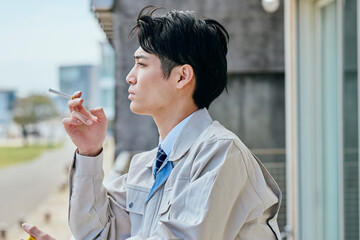 タバコ休憩をする作業服姿の男性