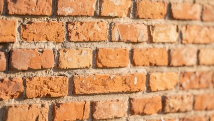 Obraz premium Close-up of a weathered brick wall, showcasing the texture and detail of the aged construction. The warm orange and red tones of the bricks contrast with the grey mortar