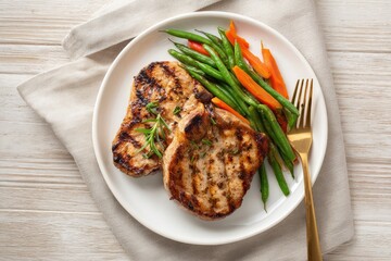 Grilled pork chops with green beans and carrots on a plate