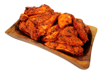 Tandoori marinated oven baked chicken meat in a wooden serving dish isolated on a white background