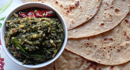 Sarson ka saag served with layered chapatis. A traditional Punjabi dish of spiced mustard greens curry, perfect for Indian winter meals. Authentic and flavorful, staple winter meal with rustic charm